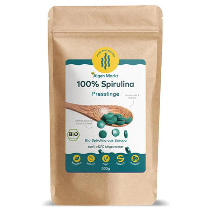 Bio Spirulina Presslinge 300g von Algenmarkt – grüne Tabletten auf Holzlöffel vor Kraftpapierbeutel