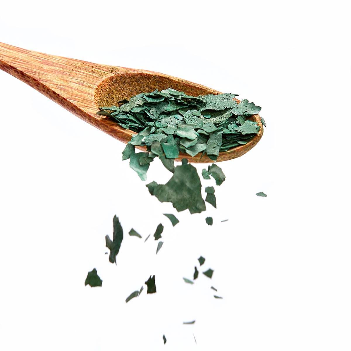 Bio Spirulina Flocken von Algenmarkt auf einem Holzlöffel vor weißem Hintergrund