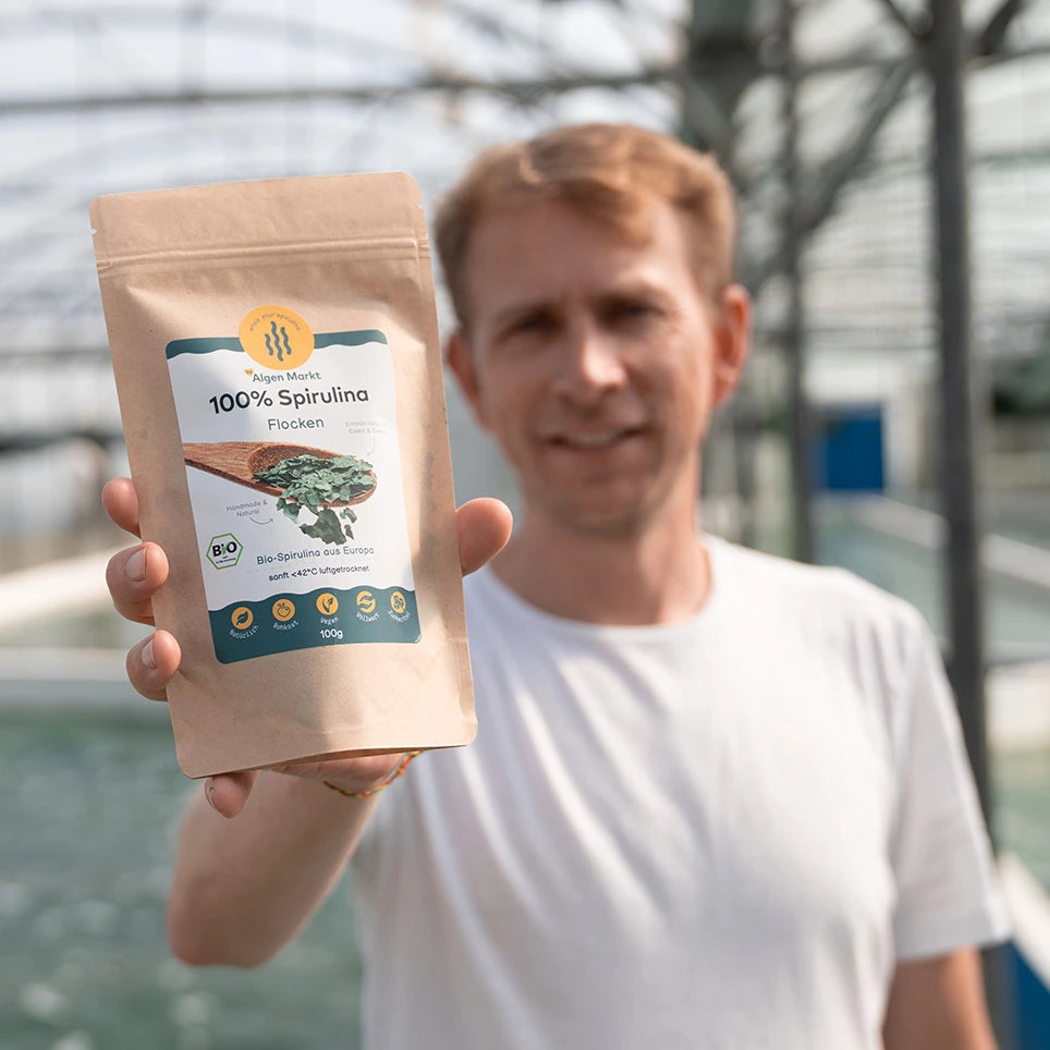 Bio Spirulina Flocken 100g von Algenmarkt in der Hand vor der Farm
